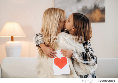 Sweet little hand drawn heart, mother's day. Woman and her daughter are together in domestic room 135605604