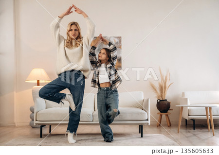 Fitness or yoga exercise. Mother and daughter are together in domestic room Fitness or yoga exercise. Mother and daughter are together in domestic room 135605633