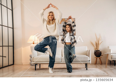 Fitness or yoga exercise. Mother and daughter are together in domestic room Fitness or yoga exercise. Mother and daughter are together in domestic room 135605634