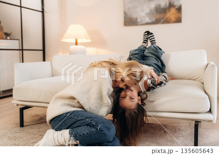 On the sofa, fun, smiling. Mother and daughter are together in domestic room 135605643