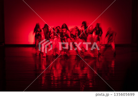 Dancers performing with motion blur under red stage lighting 135605699