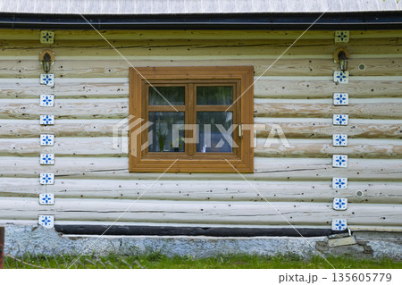 Traditional log house facade with decorative tiles in Osturna 135605779