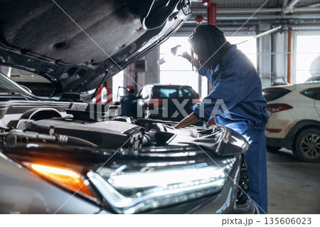 Front part, hood is opened, fixing the automobile. Male mechanic is with car in garage 135606023