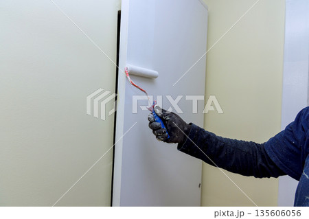 Painter is using roller brush to apply paint on wall in room wall has smooth surface. Painter is using roller brush to apply paint on wall in room wall has smooth surface. 135606056