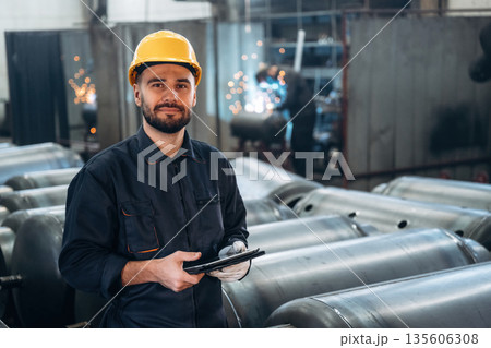 Digital tablet is in hands. Man is working in the factory Digital tablet is in hands. Man is working in the factory 135606308