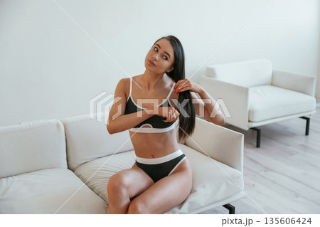 Combs the hair by hands. Young woman with slim body type is indoors Combs the hair by hands. Young woman with slim body type is indoors 135606424