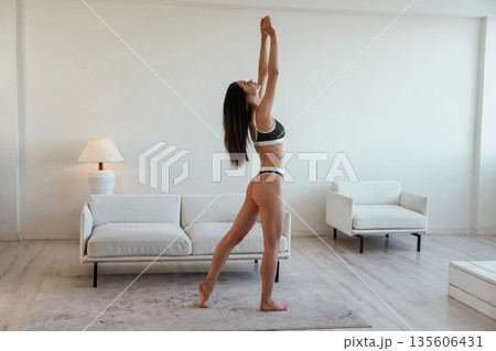 Model is standing in domestic room, posing. Young woman with slim body type is indoors Model is standing in domestic room, posing. Young woman with slim body type is indoors 135606431