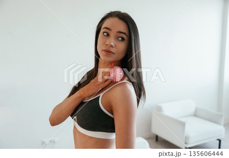 Pink color massage roller. Young woman with slim body type is indoors 135606444