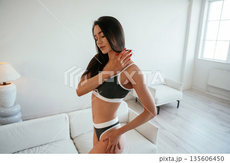 Doing massage by pink roller. Young woman with slim body type is indoors Doing massage by pink roller. Young woman with slim body type is indoors 135606450