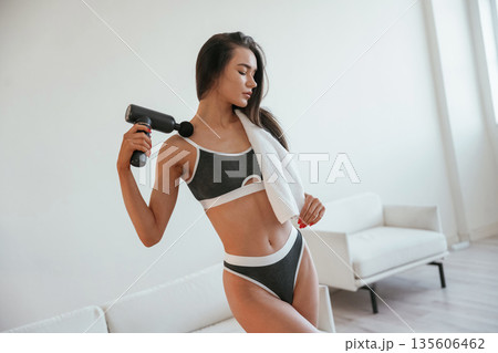 Electric massager. Young woman with slim body type is indoors 135606462
