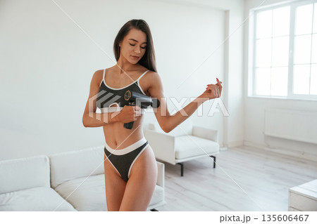 Hand massage by using electric massager. Young woman with slim body type is indoors 135606467