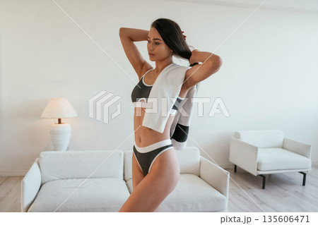 Towel on the neck. Young woman with slim body type is indoors Towel on the neck. Young woman with slim body type is indoors 135606471