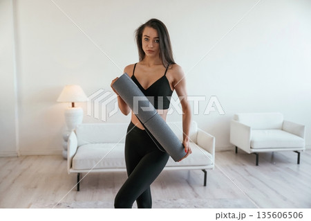 Ready for the yoga, holding mat. Young woman with slim body type is indoors 135606506