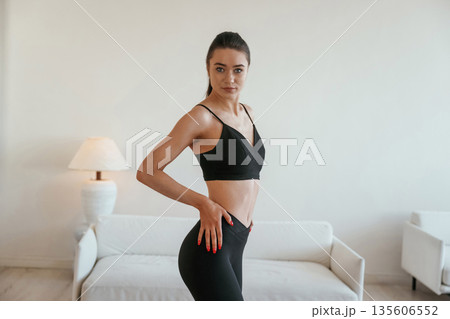 Just standing and posing. Young woman with slim body type is indoors 135606552