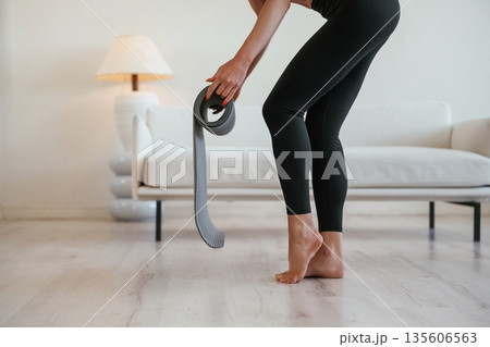 Rolling off the yoga mat. Young woman with slim body type is indoors Rolling off the yoga mat. Young woman with slim body type is indoors 135606563