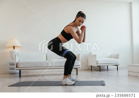 Legs work, stretching. Young woman with slim body type is indoors Legs work, stretching. Young woman with slim body type is indoors 135606571