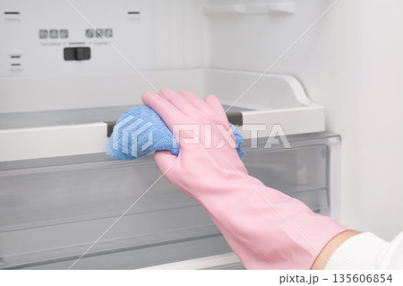 Close-up of a woman's gloved hand wiping down a refrigerator Close-up of a woman's gloved hand wiping down a refrigerator 135606854