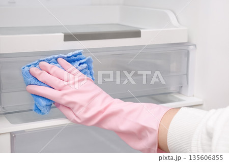 Close-up of a woman's gloved hand wiping down a refrigerator Close-up of a woman's gloved hand wiping down a refrigerator 135606855