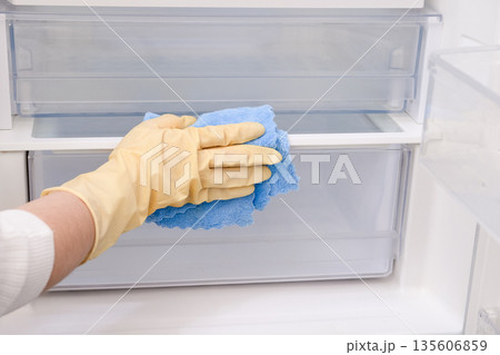 Close-up of a woman's gloved hand wiping down a refrigerator Close-up of a woman's gloved hand wiping down a refrigerator 135606859