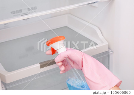 Close-up of a woman's gloved hand wiping down a refrigerator 135606860
