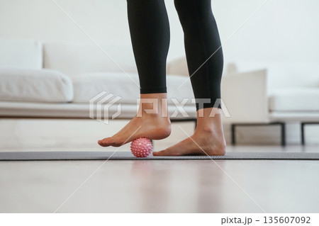 Close up view of woman's legs, on yoga mat with massager roller 135607092