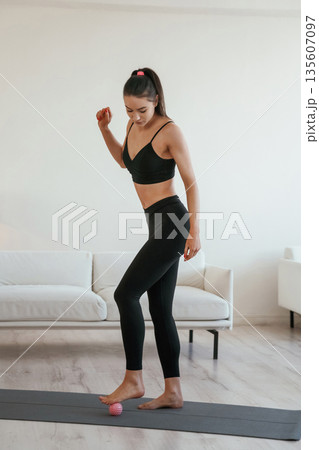 Small massage roller. Young woman with slim body type is indoors 135607097
