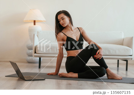 By the laptop on floor. Young woman with slim body type is indoors 135607135