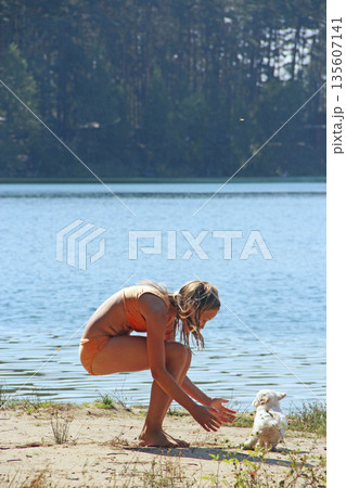 Little girl playing with puppy on the beach. Summer vacation with beloved dog 135607141