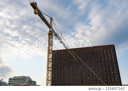 Construction crane at building area. Construction site with building crane. Industrial area. Building and construction. Hoisting crane. Construction at building site with crane 135607162