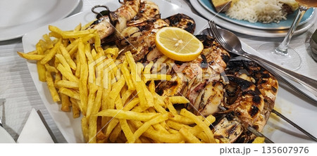 Close-up of fried potatoes and grilled shrimp. Concept of Portuguese traditional food, gastrotourism Close-up of fried potatoes and grilled shrimp. Concept of Portuguese traditional food, gastrotourism 135607976