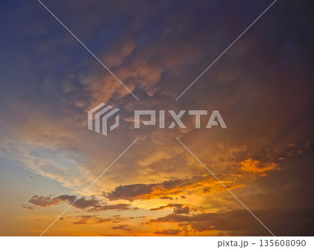 Expansive view of a dramatic sunset sky filled with textured mammatus and altocumulus clouds. Breathtaking natural scene with the horizon glowing in fiery orange hues, transiting into deep indigo Expansive view of a dramatic sunset sky filled with textured mammatus and altocumulus clouds. Breathtaking natural scene with the horizon glowing in fiery orange hues, transiting into deep indigo 135608090