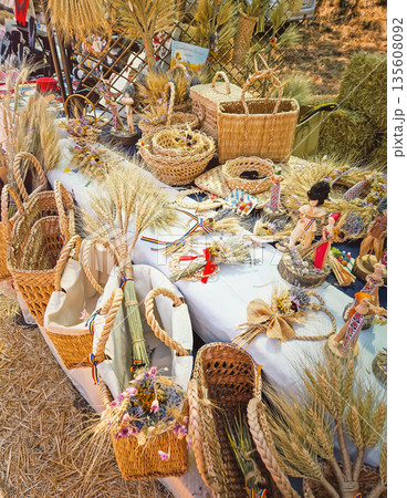 Causeni, Moldova - July 27, 2025: Traditional rustic crafts at an outdoor market. Various woven wicker baskets, intricate wheat sheaf arrangements and handmade folk dolls dressed in national costumes Causeni, Moldova - July 27, 2025: Traditional rustic crafts at an outdoor market. Various woven wicker baskets, intricate wheat sheaf arrangements and handmade folk dolls dressed in national costumes 135608092