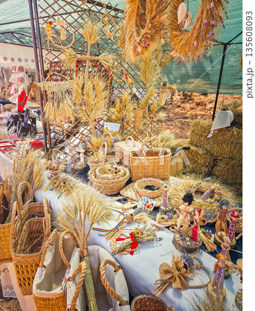 Causeni, Moldova - July 27, 2025: Traditional rustic crafts at an outdoor market. Various woven wicker baskets, intricate wheat sheaf arrangements and handmade folk dolls dressed in national costumes Causeni, Moldova - July 27, 2025: Traditional rustic crafts at an outdoor market. Various woven wicker baskets, intricate wheat sheaf arrangements and handmade folk dolls dressed in national costumes 135608093