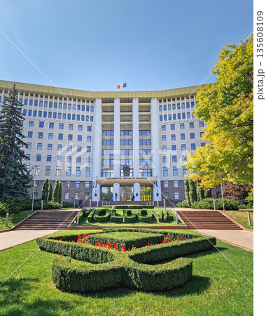 Chisinau, Moldova - September 24, 2025 Republic of Moldova parliament building with the Moldovan flag waving on the roof, and a large topiary garden with flowers in front Chisinau, Moldova - September 24, 2025 Republic of Moldova parliament building with the Moldovan flag waving on the roof, and a large topiary garden with flowers in front 135608109