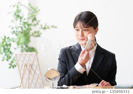鏡を見てメイクを整えるリクルートスーツ姿の女子大学生 鏡を見てメイクを整えるリクルートスーツ姿の女子大学生 135608331