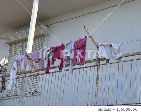 Clothes drying on a balcony rail under sunlight providing a simple urban lifestyle concept 135608356