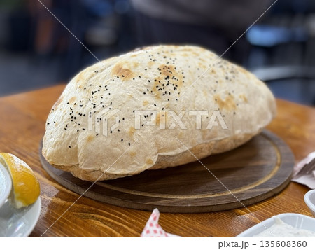 Freshly baked bread loaf with black sesame seeds, placed on wooden board in indoor setting Freshly baked bread loaf with black sesame seeds, placed on wooden board in indoor setting 135608360
