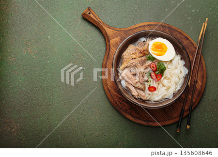 Asian soup rice noodles duck meat egg chopsticks ramen bowl green rustic background copy space Asian soup rice noodles duck meat egg chopsticks ramen bowl green rustic background copy space 135608646