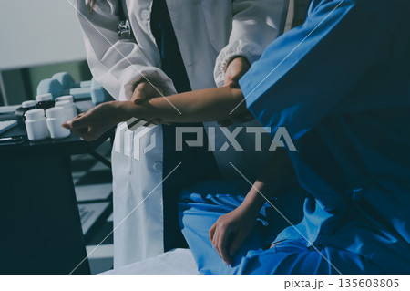 Doctor examining patient's elbow in hospital room Doctor examining patient's elbow in hospital room 135608805