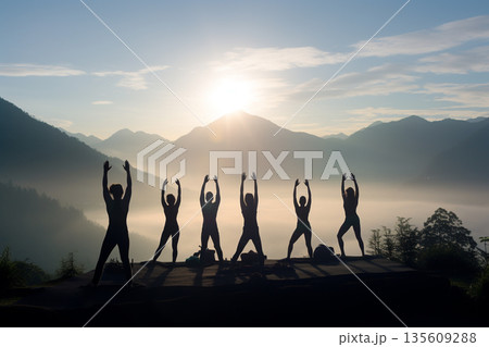 Group of people doing yoga in nature during sunset or sunrise 135609288