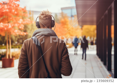 Man with headphones walking in park during autumn time Man with headphones walking in park during autumn time 135609352