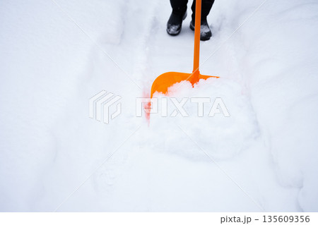 removing a lot of snow by orange plastic shovel after snowfall removing a lot of snow by orange plastic shovel after snowfall 135609356