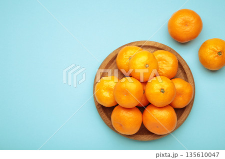 Fresh small tangerine mandarin orange in a plate on blue background. Space for text Fresh small tangerine mandarin orange in a plate on blue background. Space for text 135610047
