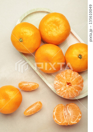 Fresh small tangerine mandarin orange in plate on light background. Vertical photo Fresh small tangerine mandarin orange in plate on light background. Vertical photo 135610049