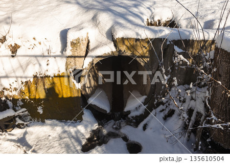 A snow-covered concrete drain pipe on a clear winter day A snow-covered concrete drain pipe on a clear winter day 135610504