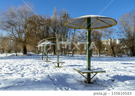 Umbrella-shaped canopies on a snowy winter beach on a clear day Umbrella-shaped canopies on a snowy winter beach on a clear day 135610583
