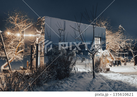 Modern mirrored cafe glowing at night. Magical winter atmosphere with reflected city lights. 135610621