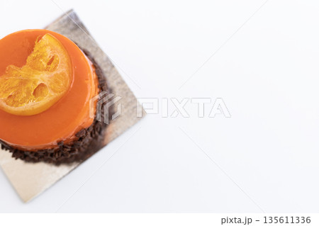 Round orange chocolate pastry decorated with an orange slice, elegant modern dessert 135611336