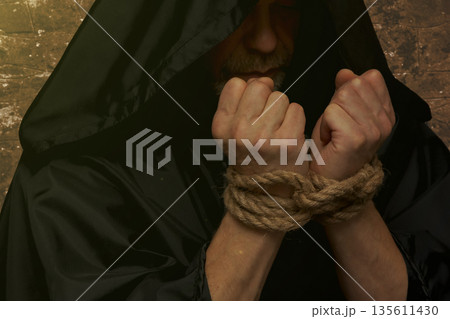 Bound monk hands holding rosary on dark background 135611430
