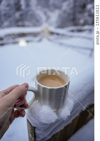 Hand Holding Coffee Mug on Wooden Fence in Snowy Winter Hand Holding Coffee Mug on Wooden Fence in Snowy Winter 135611611